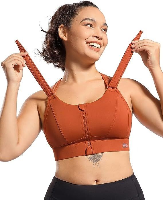 A model is adjusting the front closure straps on an orange sports bra.