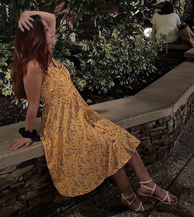 A reviewer is wearing a yellow floral dress.