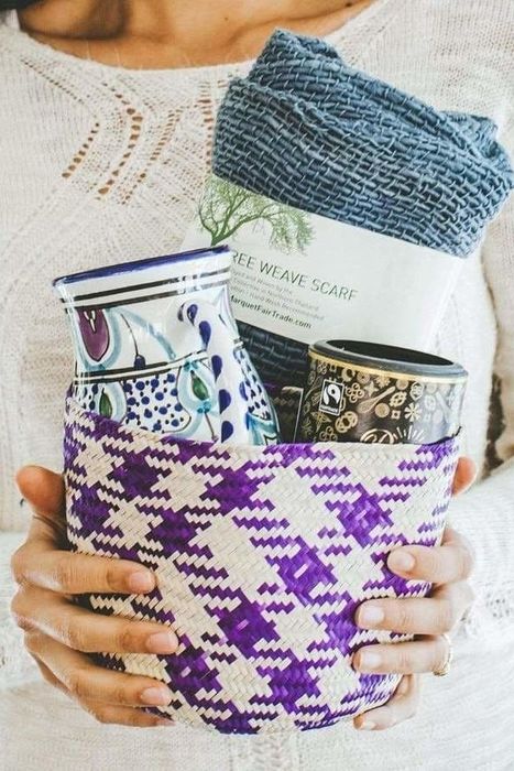 A model holding a woven basket containing a vase, scarf, and black canister.
