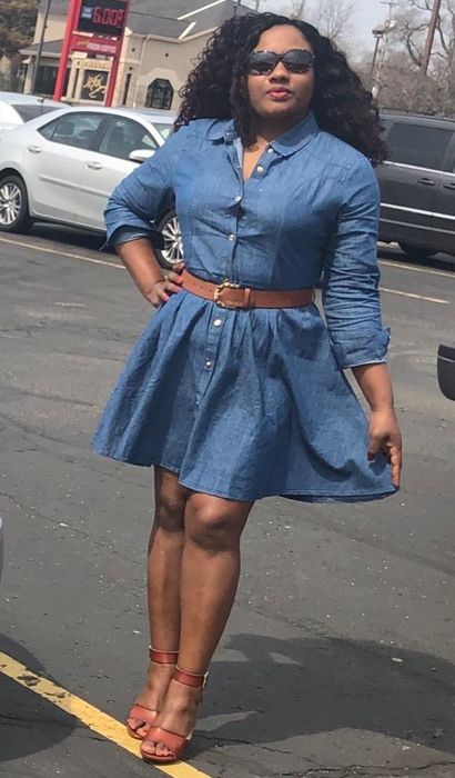 A reviewer is wearing a blue belted denim flared shirt dress.