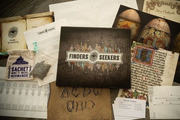 A Finders Seekers box surrounded by various papers and illustrations.