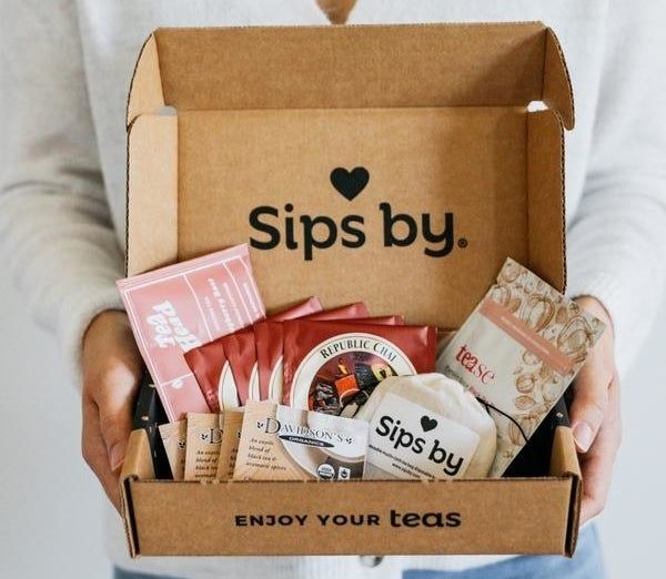 A model holding an open box filled with various types of tea