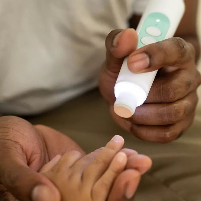A person using the nail trimmer set on a baby's hands.