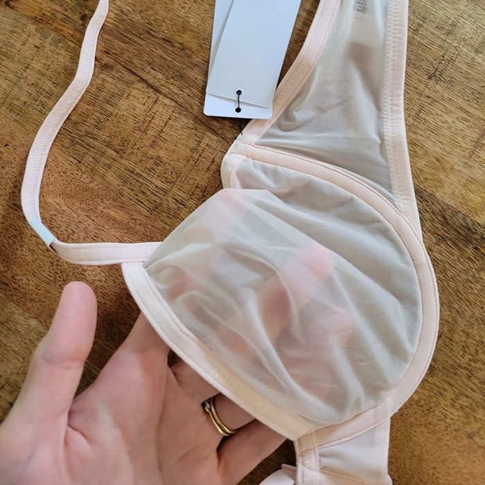 Reviewer’s photo showing a hand beneath the demi-cup to highlight the bra's sheer quality.