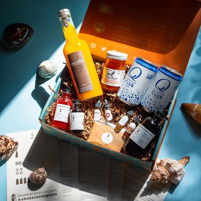 A top-down shot of an open box filled with cocktail ingredients alongside recipe cards