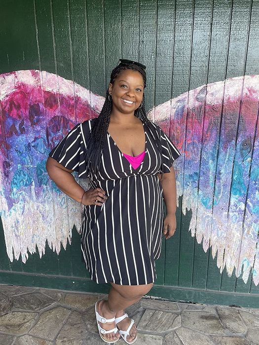 A reviewer is wearing a black V-neck wrap dress.