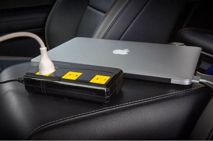 A laptop charging through a portable car charger while resting on a seat, making it the perfect solution for on-the-go power needs.