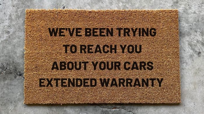 The doormat with the message 'We’ve Been Trying to Reach You About Your Car’s Extended Warranty'