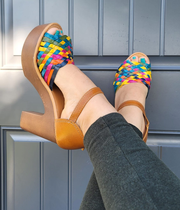 A model’s feet are shown in colorful wedges paired with leggings.