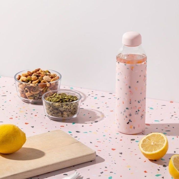 A pink glass water bottle featuring a terrazzo design