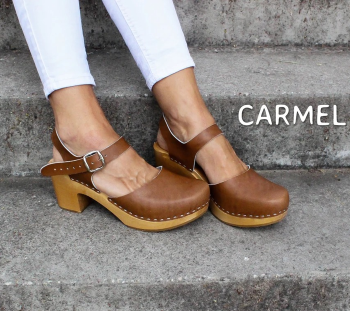 A model's feet elegantly showcasing brown wooden clogs.