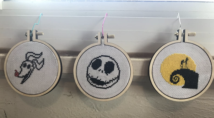 A customer review photo showcasing three completed cross-stitch patterns, each beautifully crafted