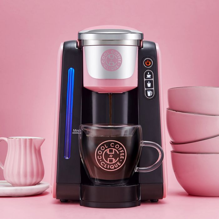 A sleek black and pink coffee machine brewing coffee into a glass mug.