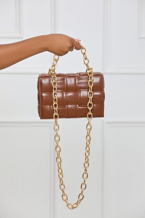 A brown rectangular woven bag, accented with gold hand and shoulder chains, for a touch of elegance.