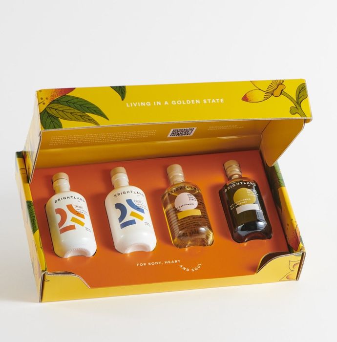 A yellow box containing four small bottles of olive oil neatly packed inside.