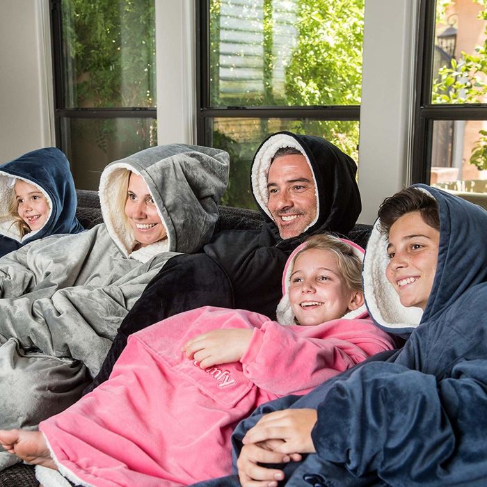 A family snuggling together, each wearing one of the cozy hoodie blankets.