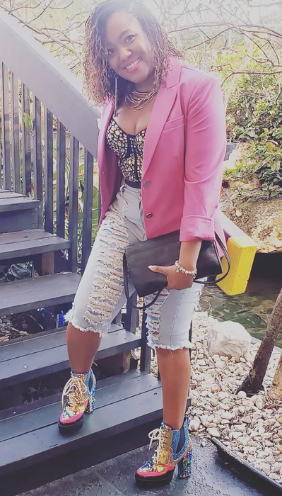 A reviewer is wearing the boots paired with jeans and a pink blazer.