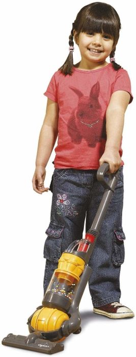 A child is enthusiastically pushing the Dyson vacuum across the floor, adding some fun to their cleaning routine.