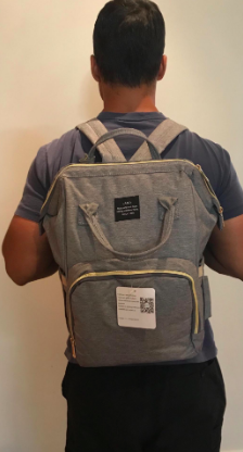 A reviewer’s photo of someone wearing the diaper bag like a regular backpack, demonstrating its easy and practical design.