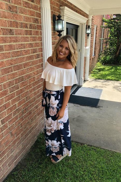 A reviewer is dressed in floral wide-leg pants.