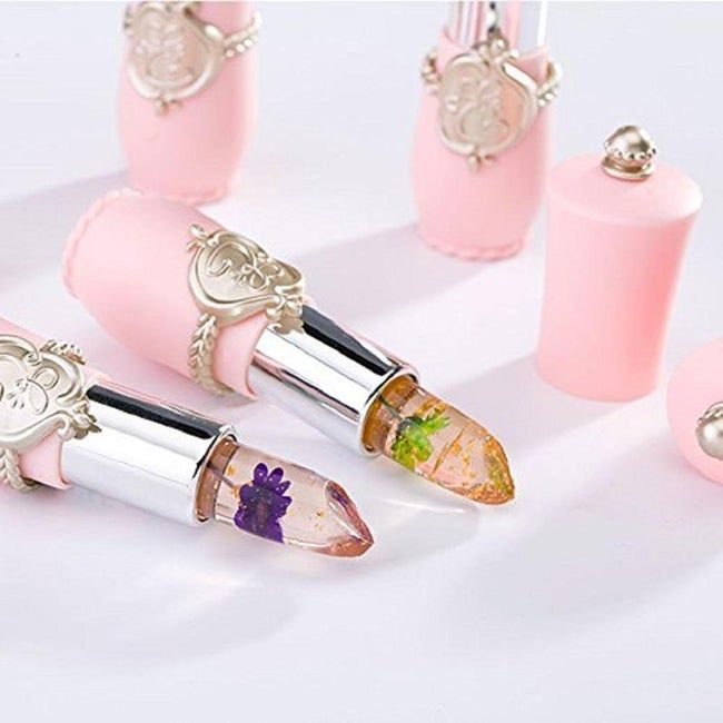 A lip balm infused with sparkles and a flower inside, set against a pink base.