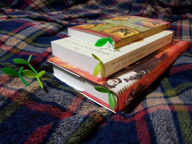 Little sprout bookmarks nestled in several books, as shown by a reviewer