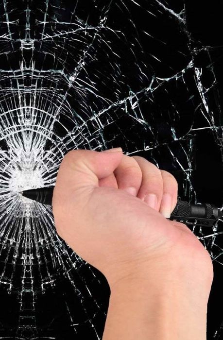 A person holding the pen to break glass, showcasing its emergency use in a dangerous situation.
