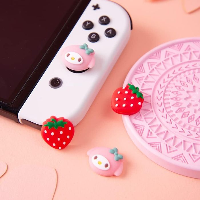 A product photo featuring two sets of joystick caps resembling a Sanrio character and strawberries