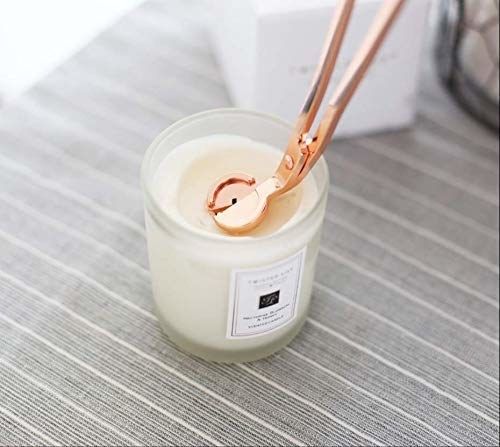 A rose gold wick trimmer being used on a candle.