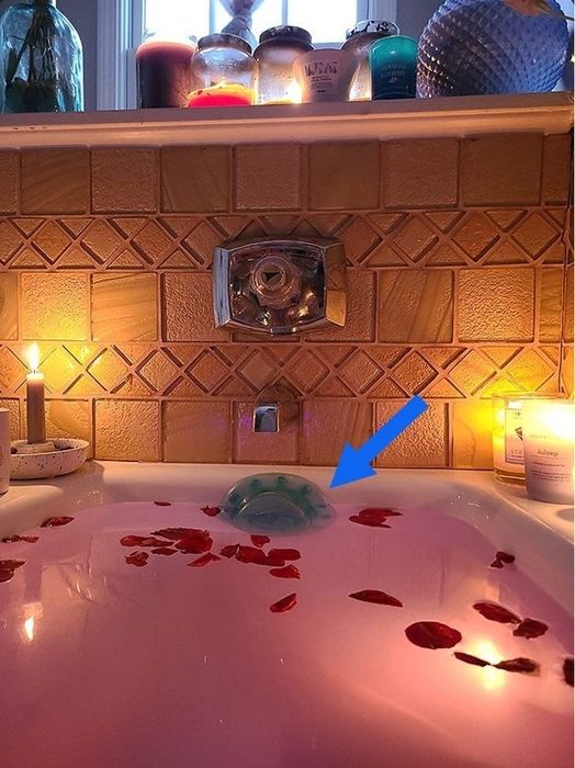 A blue suction cup drain cover placed in a tub, with bathwater almost spilling over the edges