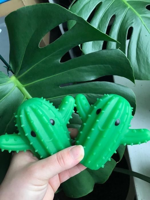 A hand holding two cactus-shaped dryer balls