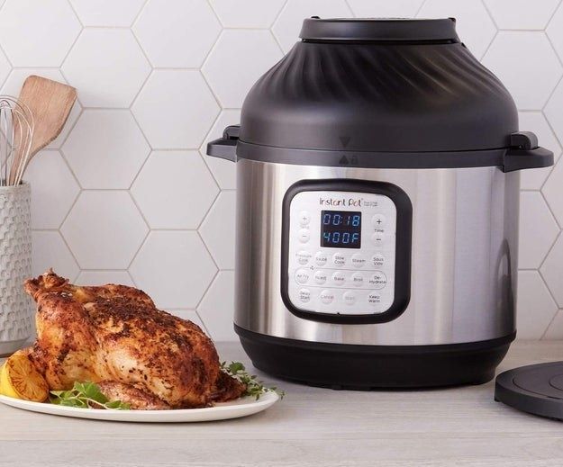 A silver and black Instant Pot with the control panel displayed next to a cooked chicken.