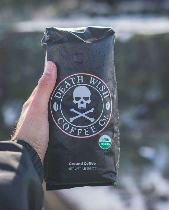 A hand holding up a coffee bag featuring a skull and crossbones design.