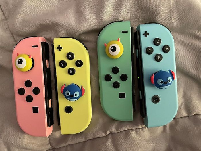 A reviewer showing the joystick caps attached to two pairs of Joy-Cons