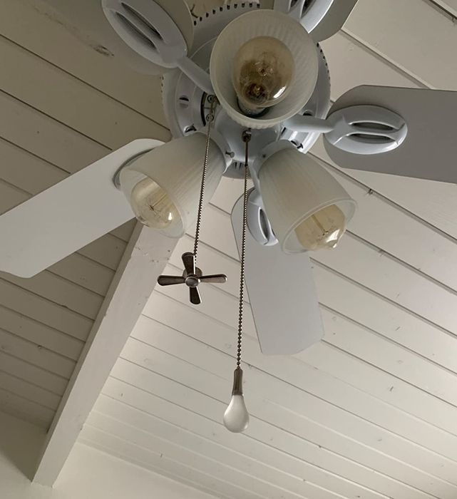 A ceiling fan with pull cords for both the fan and light bulb attached to it