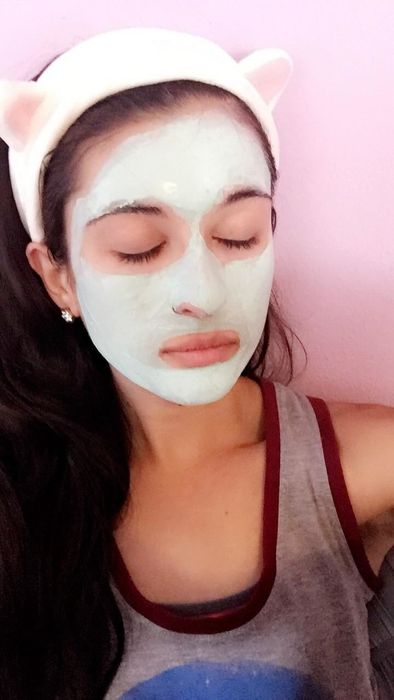 A reviewer wearing the cat ear headband while applying a face mask.