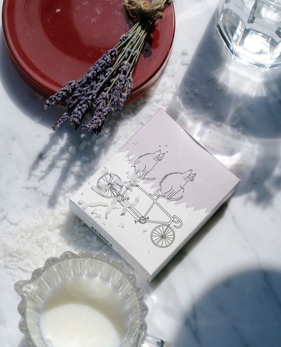 A soap with a paper label featuring an illustration of cats on a tandem bicycle