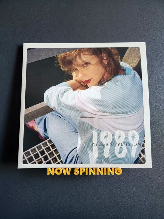 1989 Taylor's Version vinyl resting on a golden 'Now Spinning' shelf