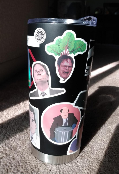 A tumbler adorned with Office stickers.