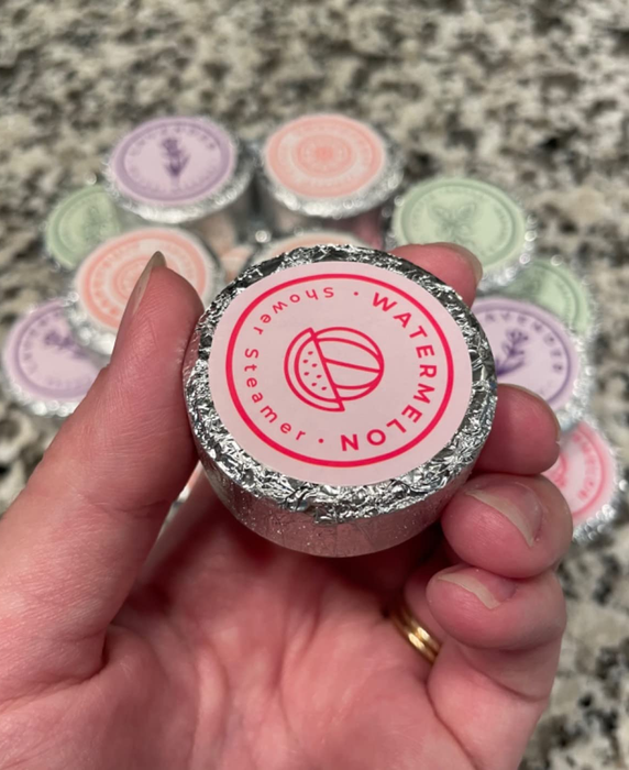 A reviewer holding one of the shower steamers in their hand