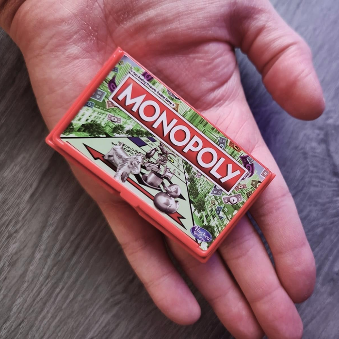 A reviewer holding the miniature version of Monopoly for size comparison