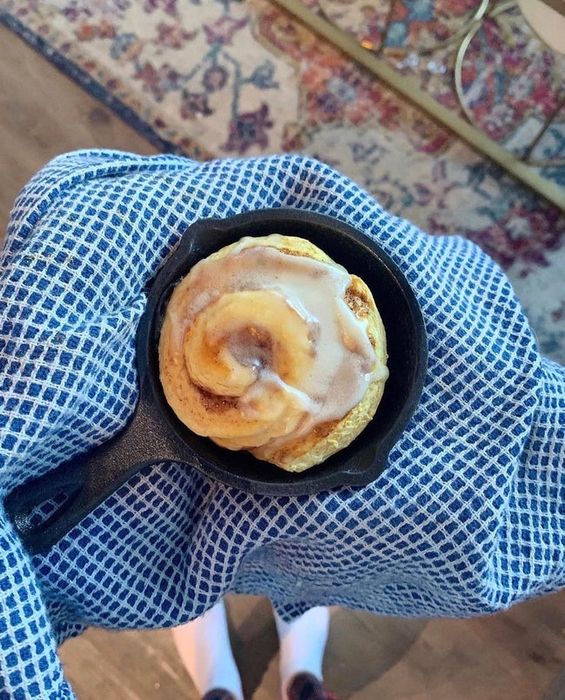 A mini cast iron skillet filled with a single cinnamon roll
