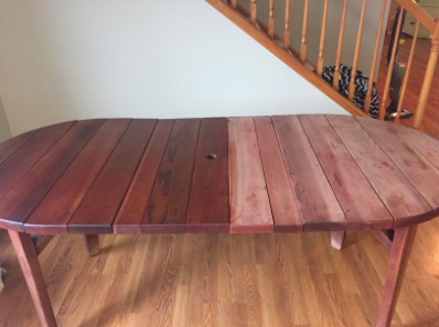 A reviewer’s photo showing half of a dining table treated with the wood polish, with the other half left untreated to demonstrate the noticeable difference.