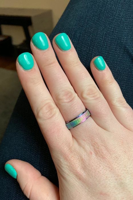 A hand adorned with a rainbow-colored ring.