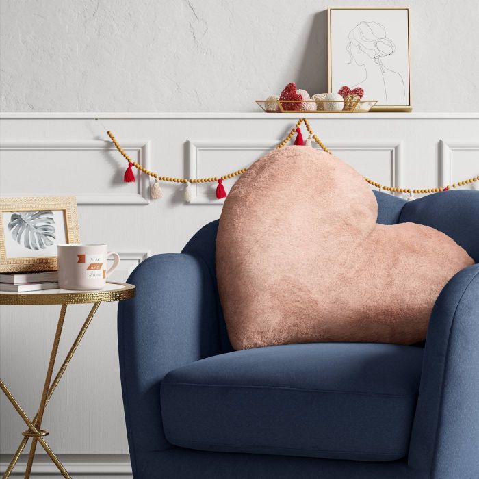 This large heart-shaped pillow in pink is perfect for taking up the entire back of a loveseat, adding comfort and warmth to your space.