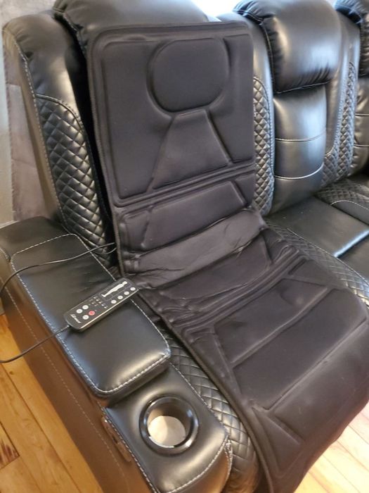 An electric massage chair with quilted upholstery, featuring a remote control on the armrest and a convenient cup holder. This chair is ideal for creating a relaxing environment in your home.