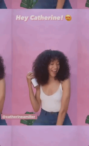 A model applying the curl refresher spray to their curly hair.