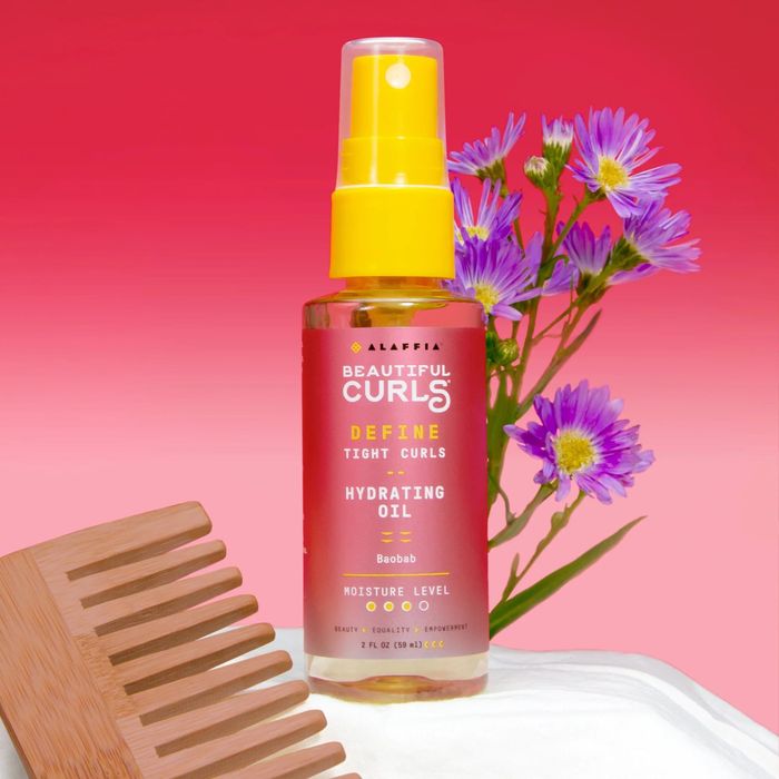 A bottle of hydrating oil set against a pink background.