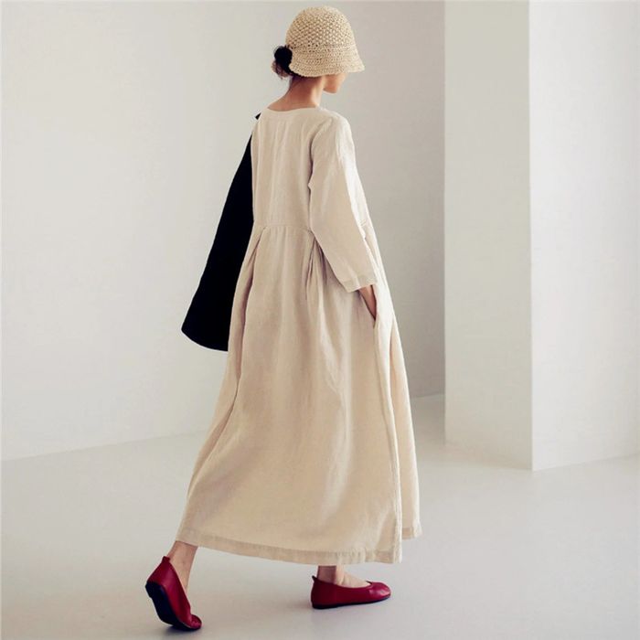 The view from the back of a model wearing a cream-colored dress paired with red flats.