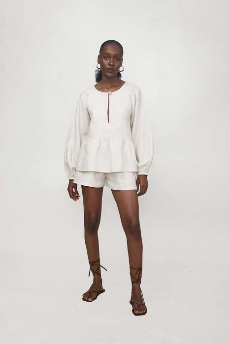 A model is seen wearing a white top and shorts set paired with brown strappy sandals.